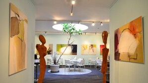 Un intérieur moderne agrémenté d’œuvres d’art abstraites aux murs, d’une plante au centre et d’un espace salon circulaire.