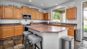 A modern kitchen with wooden cabinets, a granite countertop, a stainless steel sink, and a large window providing a view of the outdoors. - Spacious 5 BR, 3.5 BA, 4000+sf, WiFi, Pool,Hot Tub (Gilbert)