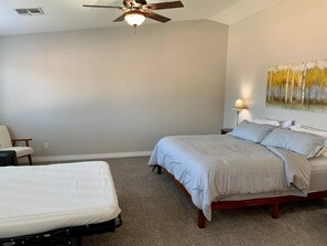 A bedroom with a bed, a chair, a ceiling fan, and a wall painting. - Spacious 5 BR, 3.5 BA, 4000+sf, WiFi, Pool,Hot Tub (Gilbert)