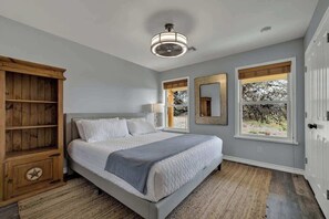 A bedroom with a bed, wooden cabinet, two windows, and a ceiling fan.