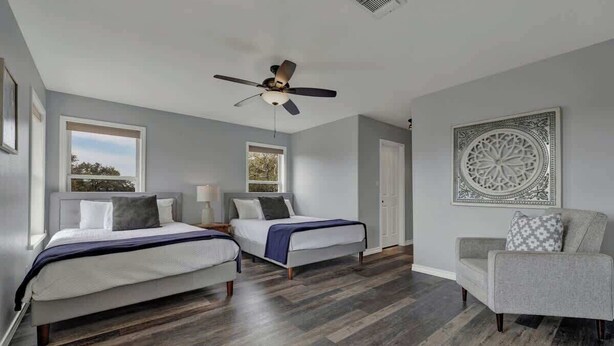 A bedroom with two beds, a ceiling fan, and a large decorative wall piece. - Starlight Meadows Hot-tub 3mi to Downtown (Fredericksburg)
