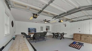Un grand espace intérieur comprenant une table de billard, des sièges et un ventilateur de plafond.