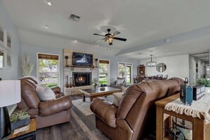 A spacious living room with leather sofas, a fireplace, and a television.