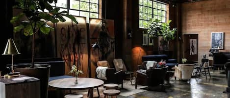 A spacious lounge with a large window, a round wooden table, and several seating options.