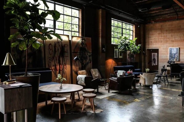 A spacious lounge with a large window, a round wooden table, and several seating options.