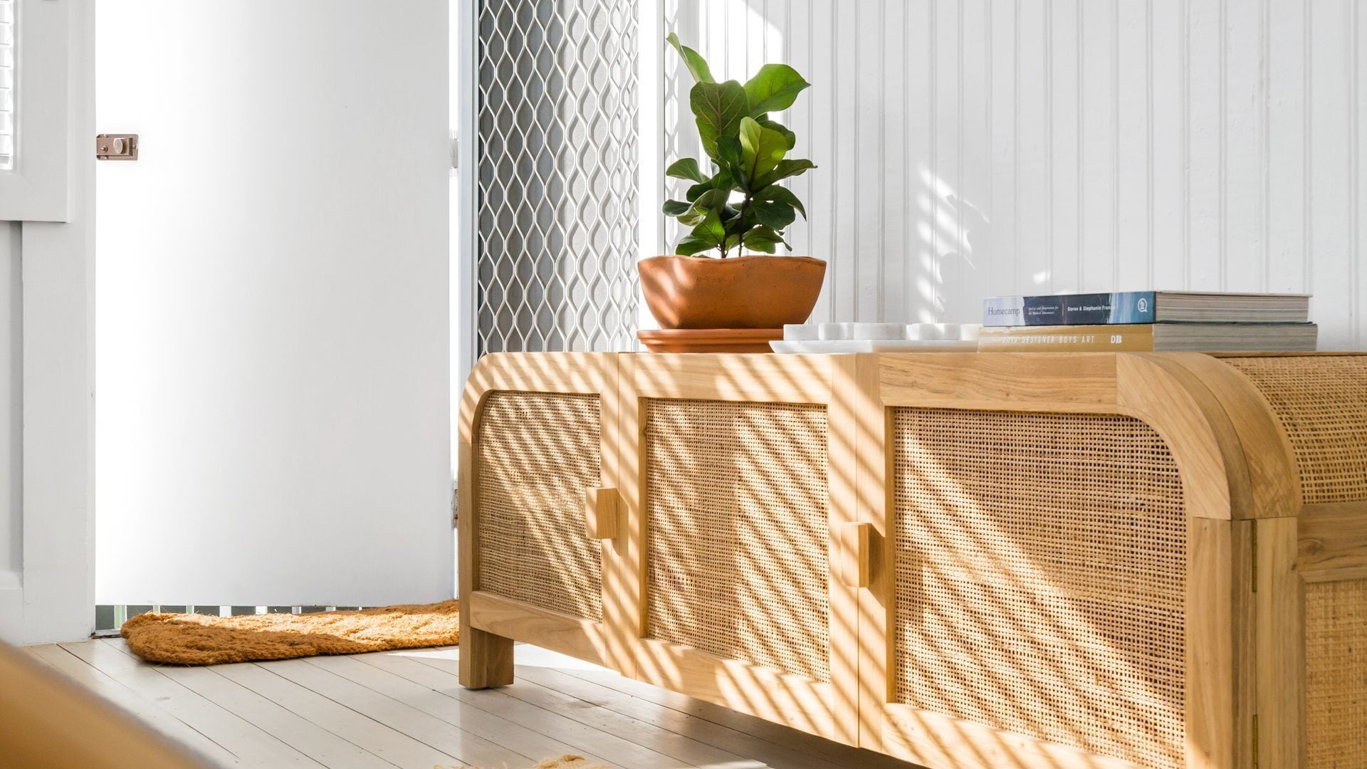 A room with a wooden console table, a potted plant, and a white wall.