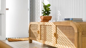 A wooden console with a woven back panel, a potted plant on top, and a stack of books beside it. - Bella BAY 2 Upstairs - Prime Location - Holiday Yamba (Yamba)