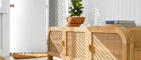 A room with a wooden console table, a potted plant, and a white wall.