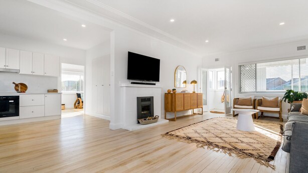 A spacious living area with a fireplace, a television mounted above it, and a large window providing natural light. - Bella BAY 2 Upstairs - Prime Location - Holiday Yamba (Yamba)