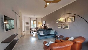 Una sala de estar moderna con sofá, mesa de centro y sillones de cuero. En el fondo, un comedor con mesa y sillas.