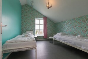 Ein Schlafzimmer mit zwei Betten, einem Fenster mit rosa Vorhang und einer Chandelier.