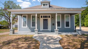 A single-story house with a front porch, a central door, and a small overhang above the door. - Gorgeous, Family-Friendly Home Near Downtown (San Antonio)