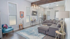A modern living room with a sectional sofa, a blue armchair, a floor lamp, and a large window. - Gorgeous, Family-Friendly Home Near Downtown (San Antonio)