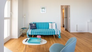 A modern living room with a striped blue sofa, a small round table with a vase of flowers, and a blue armchair. - La Grande Plage - Three Bedroom Apartment, Sleeps 5 (Saint-Cast-le-Guildo)