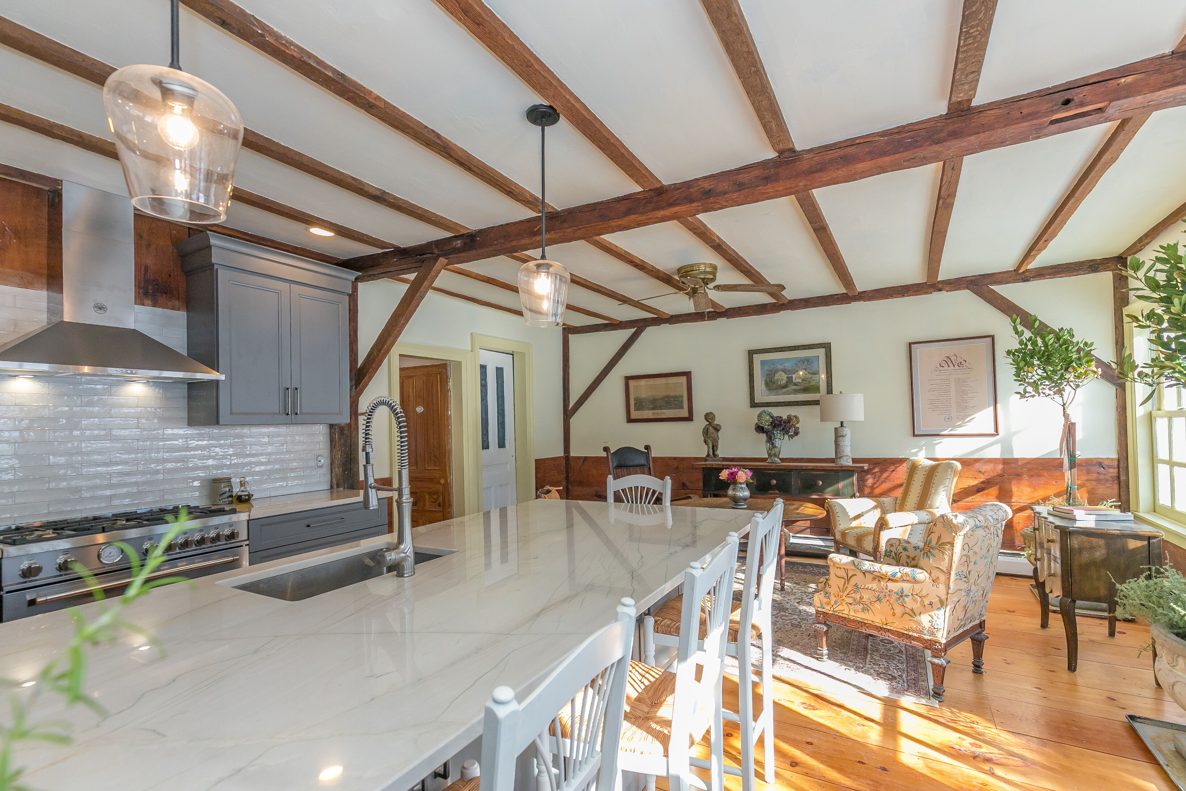 A spacious kitchen with a large island, wooden beams, and modern appliances.