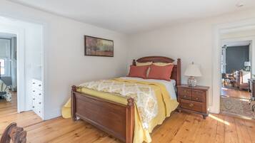 Une chambre à coucher avec un lit en bois, une table de chevet, une lampe et un tableau accroché au mur.