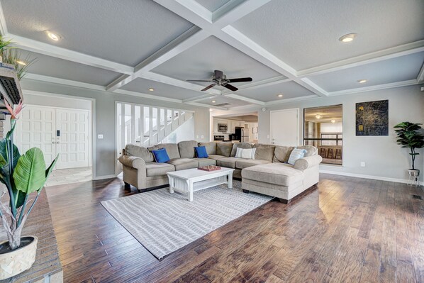 A spacious living room with a large sectional sofa, a coffee table, and a ceiling fan.