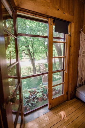 Un intérieur en bois avec une grande porte-fenêtre coulissante donnant sur un espace extérieur agrémenté de plantes en pot.