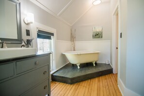 Une salle de bain avec une baignoire sur pieds, une commode et une fenêtre.