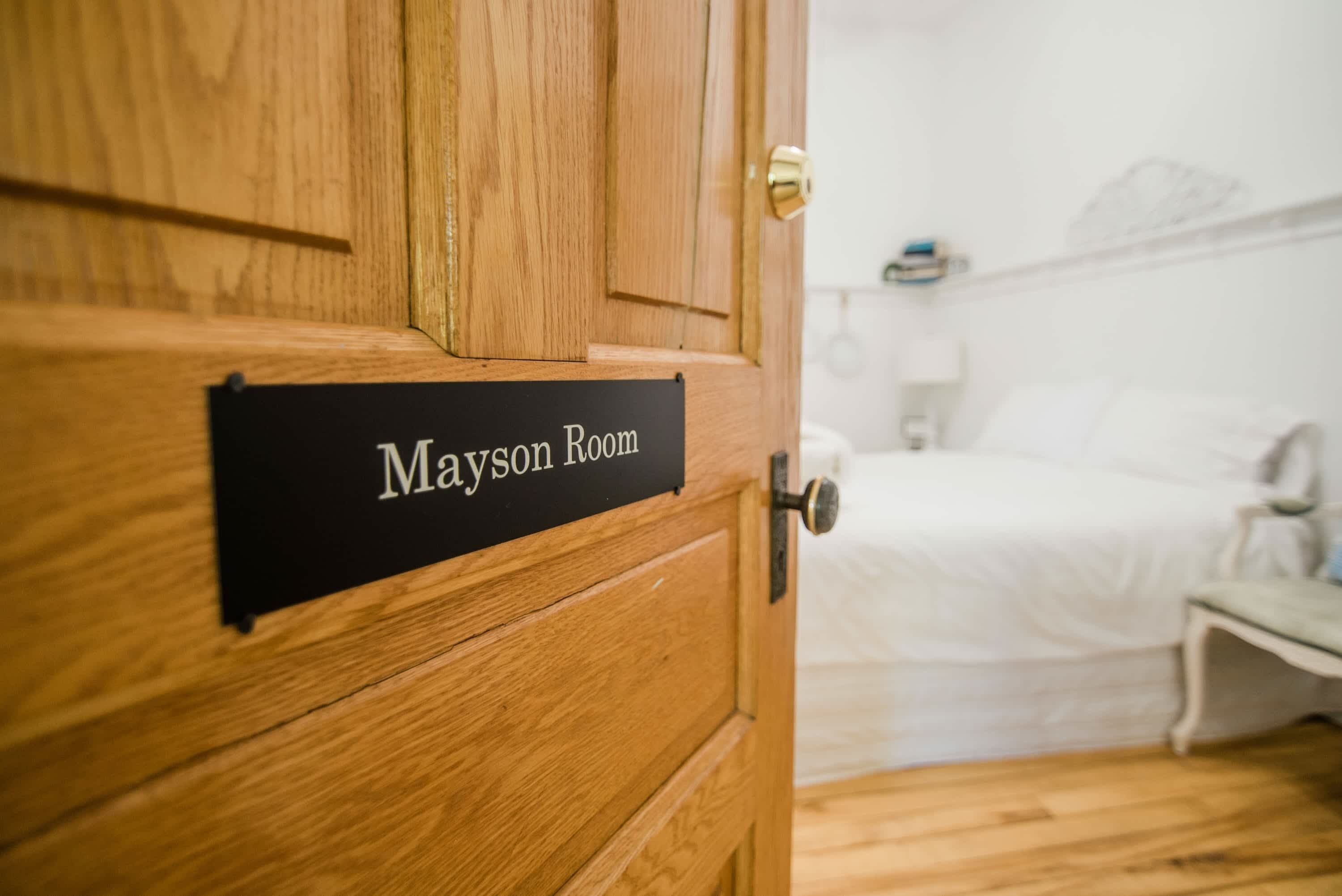 Une porte en bois sur laquelle est apposée une plaque indiquant « Mayson Room ».