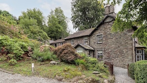 A stone house with a gravel driveway and a wooden fence. - Eller Close House (Ambleside)