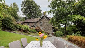 A stone house with a garden and a wooden table with wicker chairs. - Eller Close House (Ambleside)