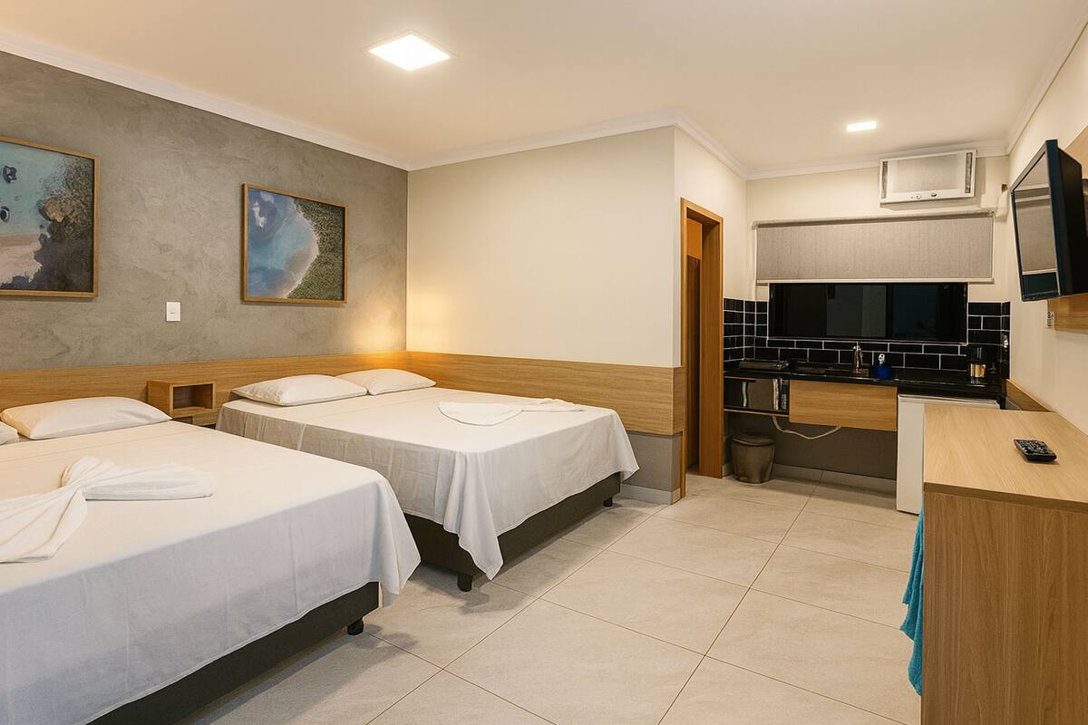 A hotel room with two beds, a kitchenette, and artwork on the walls.