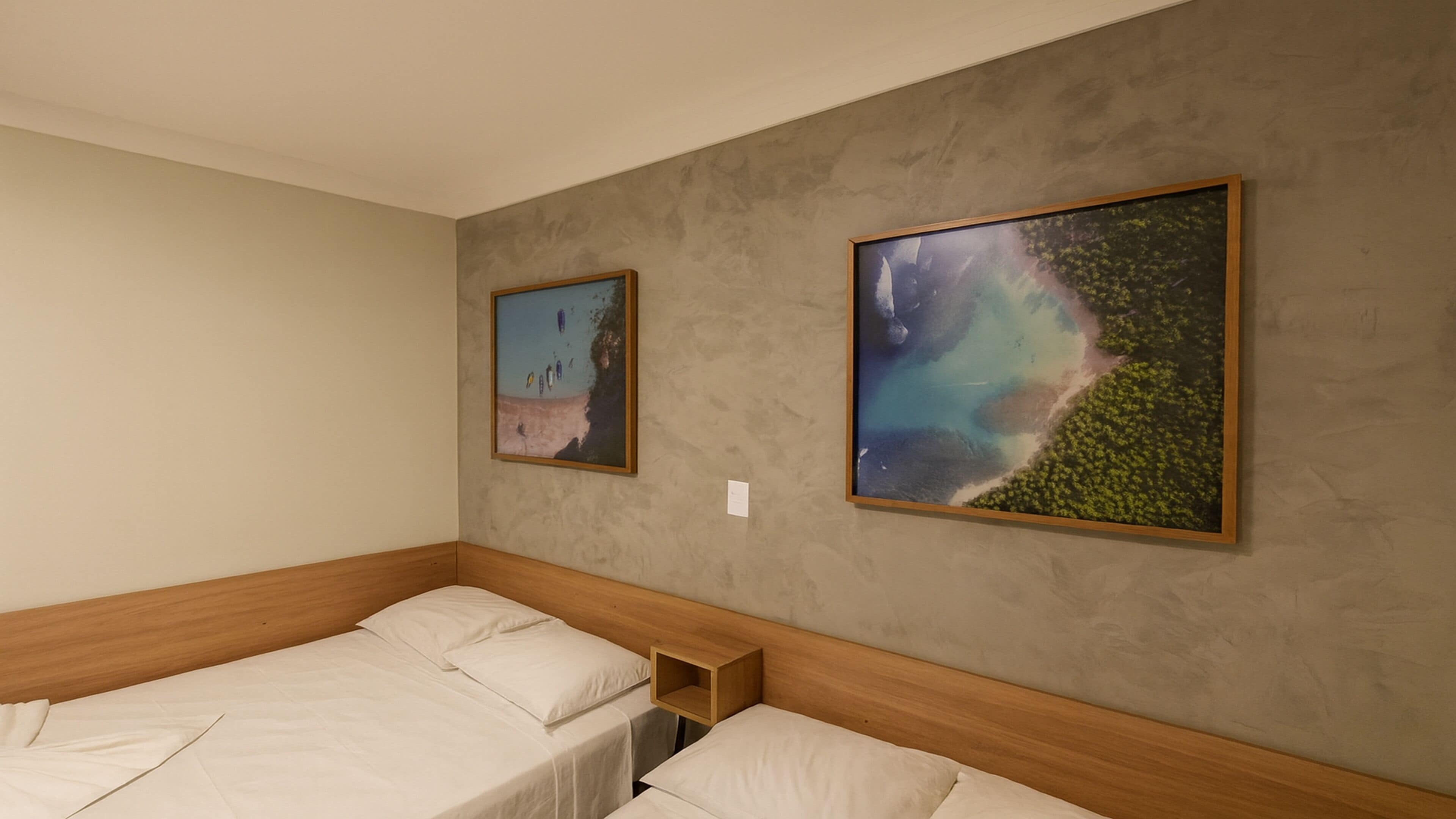 Une chambre d’hôtel avec deux lits, une tête de lit en bois et deux tableaux encadrés accrochés au mur.