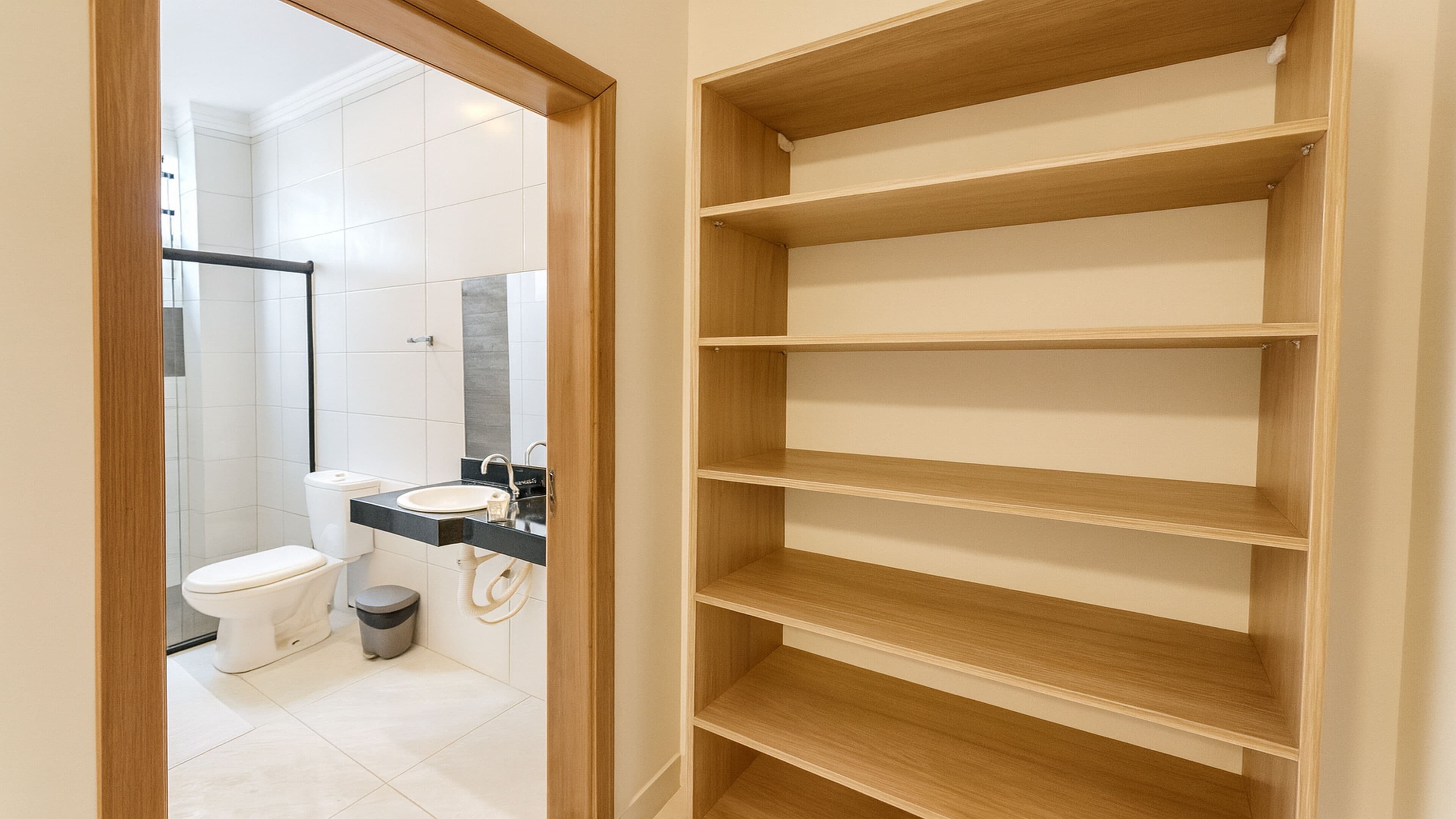 Une salle de bain moderne équipée de toilettes, d’un lavabo et d’une étagère en bois.