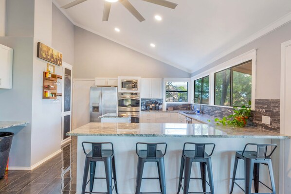 A modern kitchen with a large island, stainless steel appliances, and a bar area with stools. - Pine Top View with the Club House, Sauna, Pool (Bastrop)