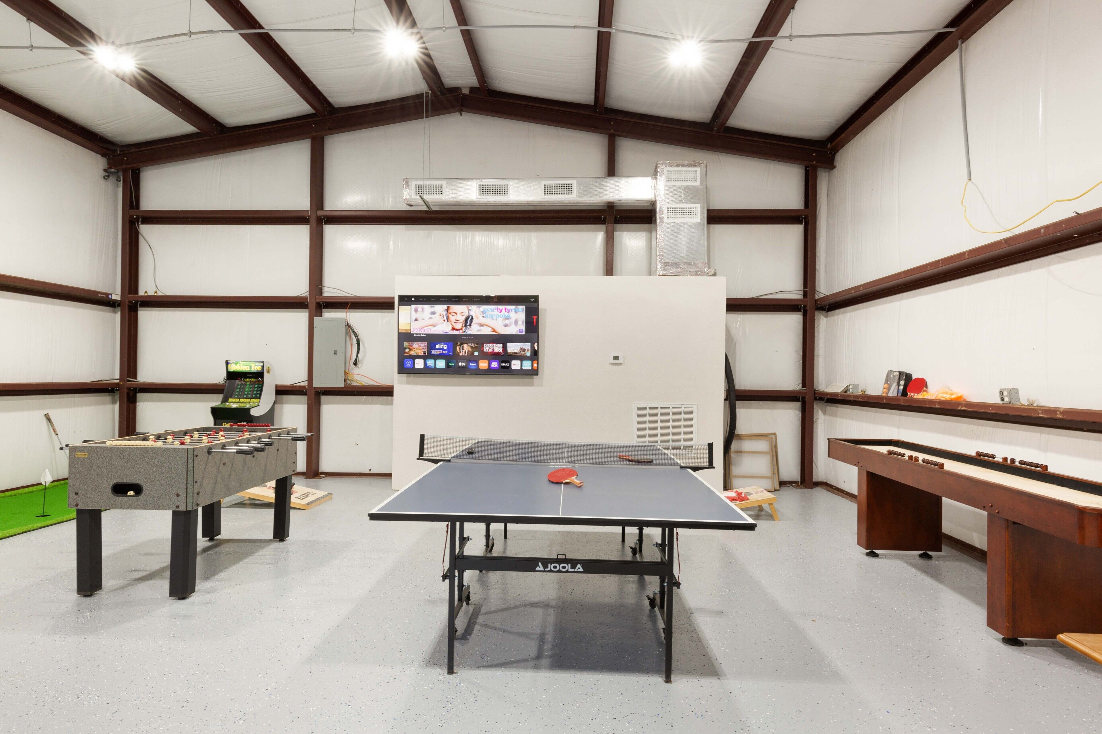 A spacious indoor area with a ping pong table, foosball table, and a billiards table.