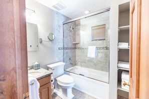 Een moderne badkamer met een douchecabine van glas, een toilet en een wastafel.
