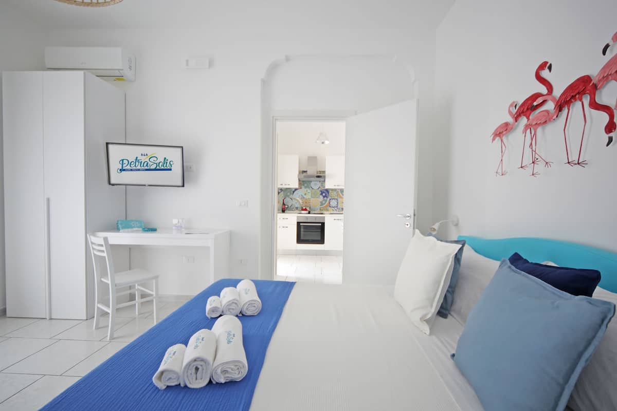 Una habitación de hotel con cama, escritorio y kitchenette.