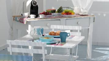 Ein Esstisch mit Kaffeemaschine, Obstschale, Croissants und Teekanne.