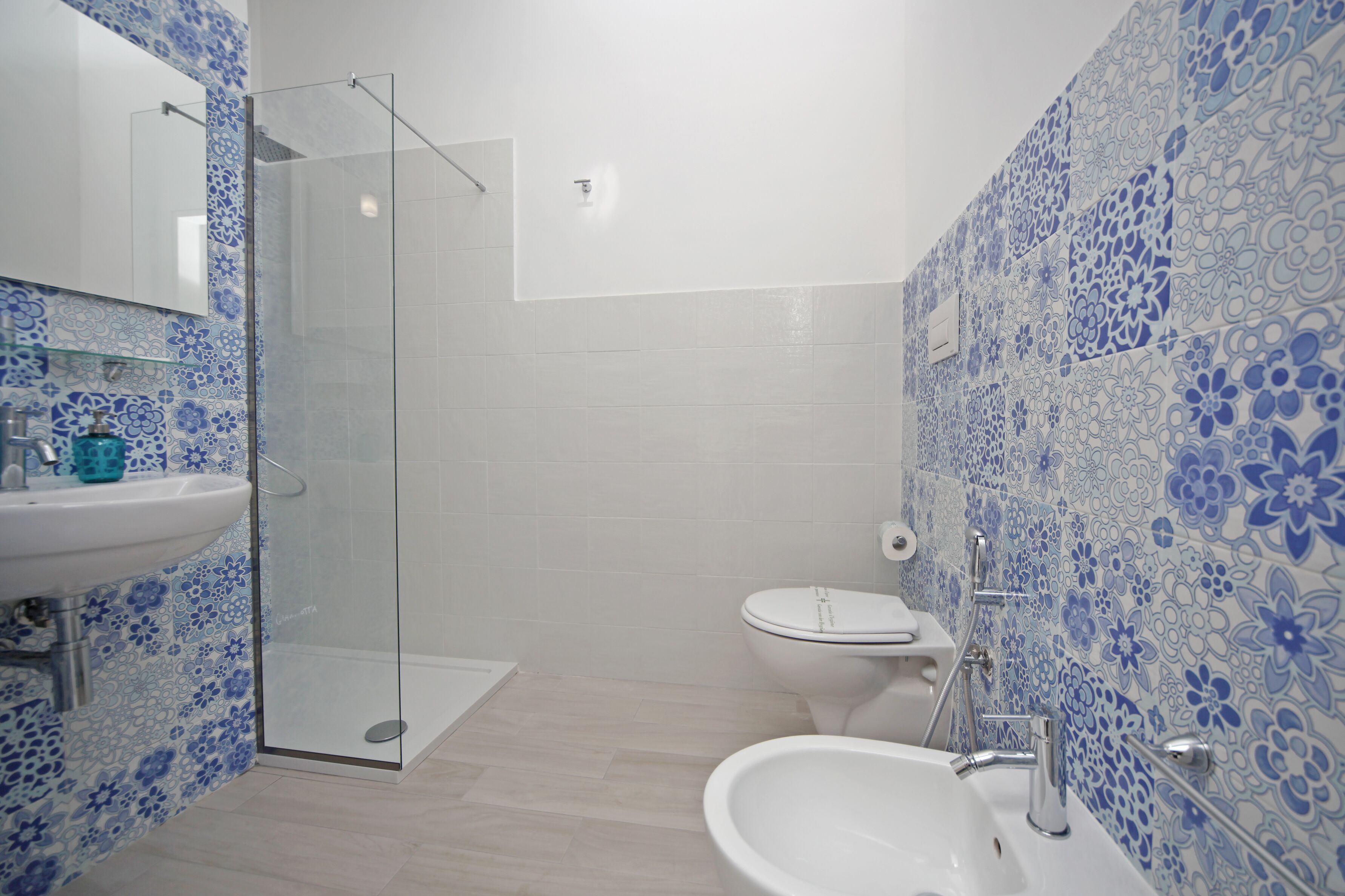 A bathroom with a glass shower enclosure, a sink, and a toilet.