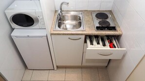A compact kitchen with a built-in microwave, a sink, and a stovetop. - one-room apartment navigli accommodation (Milano)