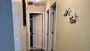 Un couloir doté d’un plancher en bois, de portes blanches et d’un élément décoratif mural.