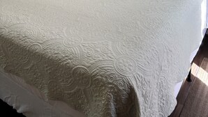 Un lit avec une couette, une table de chevet avec une lampe et une porte.