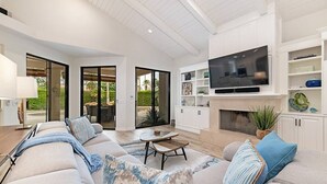 Una sala de estar moderna con un televisor de pantalla plana grande, un juego de sofá, una mesa de centro y una chimenea.
