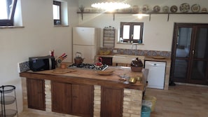 A kitchen with a wooden island, a stove, a kettle, and a refrigerator.