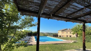Ein Poolbereich mit Liegestühlen und einer Pergola.