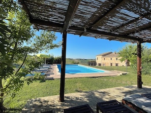 A pool area with lounge chairs and a pergola.