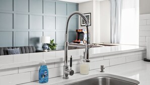 Una cocina moderna con un lavamanos de acero inoxidable, un grifo con manguera flexible y un dispensador de jabón en la encimera.