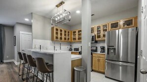 Una cocina moderna con una isla central, electrodomésticos de acero inoxidable y armarios de madera.
