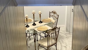 Un comedor con mesa de vidrio, cuatro sillas y candelabros.