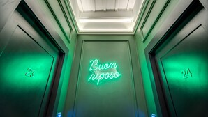 An elevator interior with green lighting and a neon sign that reads "Buon riposo". - Palazzetto Trevi (Rome)