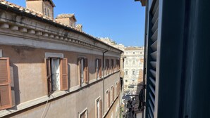 A narrow street with buildings on either side, featuring traditional architecture with shuttered windows and a cobblestone path. - Palazzetto Trevi (Rome)