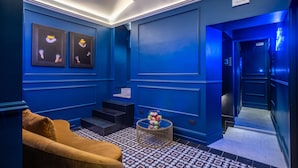 A room with blue walls, a patterned floor, a yellow sofa, and framed artwork on the wall. - Palazzetto Trevi (Rome)