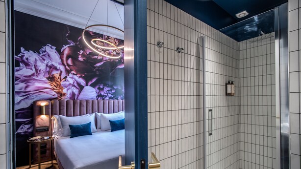 A modern bathroom with a shower, a bed with a headboard, and a wall-mounted light fixture. - Palazzetto Trevi (Rome)