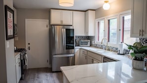 A modern kitchen with stainless steel appliances, a marble countertop, and a window with a view.